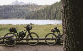 Marin Pine Mountain 2 and another mountain bike leaning up against a fence with a mountain lake behind.