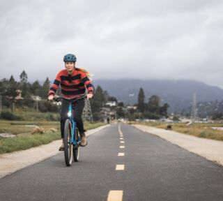 Marin Ambassador Juliet Elliott riding a Larkspur E towards the camera on a straight bike path, Mill Valley, CA.