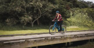 Marin Ambassador Juliet Elliott riding a Larkspur E across a wooden bridge.