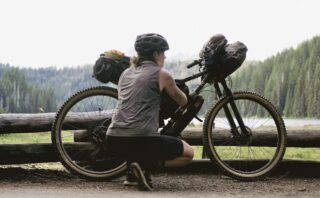 Woman crouching down in front of a Marin Pine Mountain 2 bike, loaded with bikepacking bags.