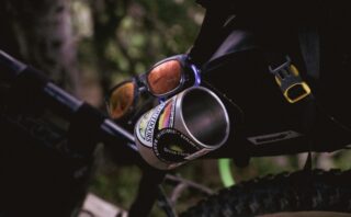 Sunglasses and a coffee mug hanging from a bike.