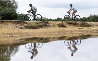 Marin Nicasio riders on an embankment with reflections in the water below, UK.