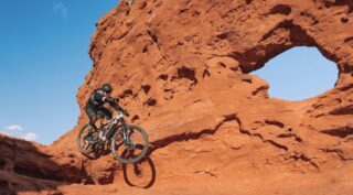 Alpine Trail E2 rider drops next to a natural arch, Utah.